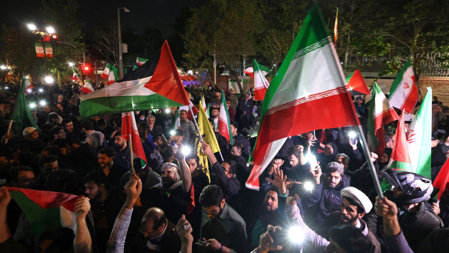 Demonstrators wave Iranian and Palestinian flags as they gather in front of the British Embassy in Tehran on April 14, 2024, after Iran launched a drone and missile attack on Israel.