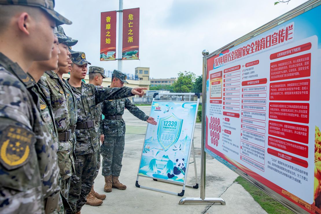 Chinese soldiers look at a poster promoting national security in the southwestern city of Beihai on National Security Education Day on April 15, 2024.