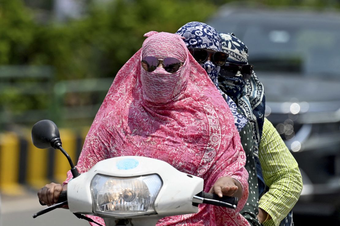 Women cover their faces with a cloth on a hot day, in Raipur, India, on April 15, 2024.