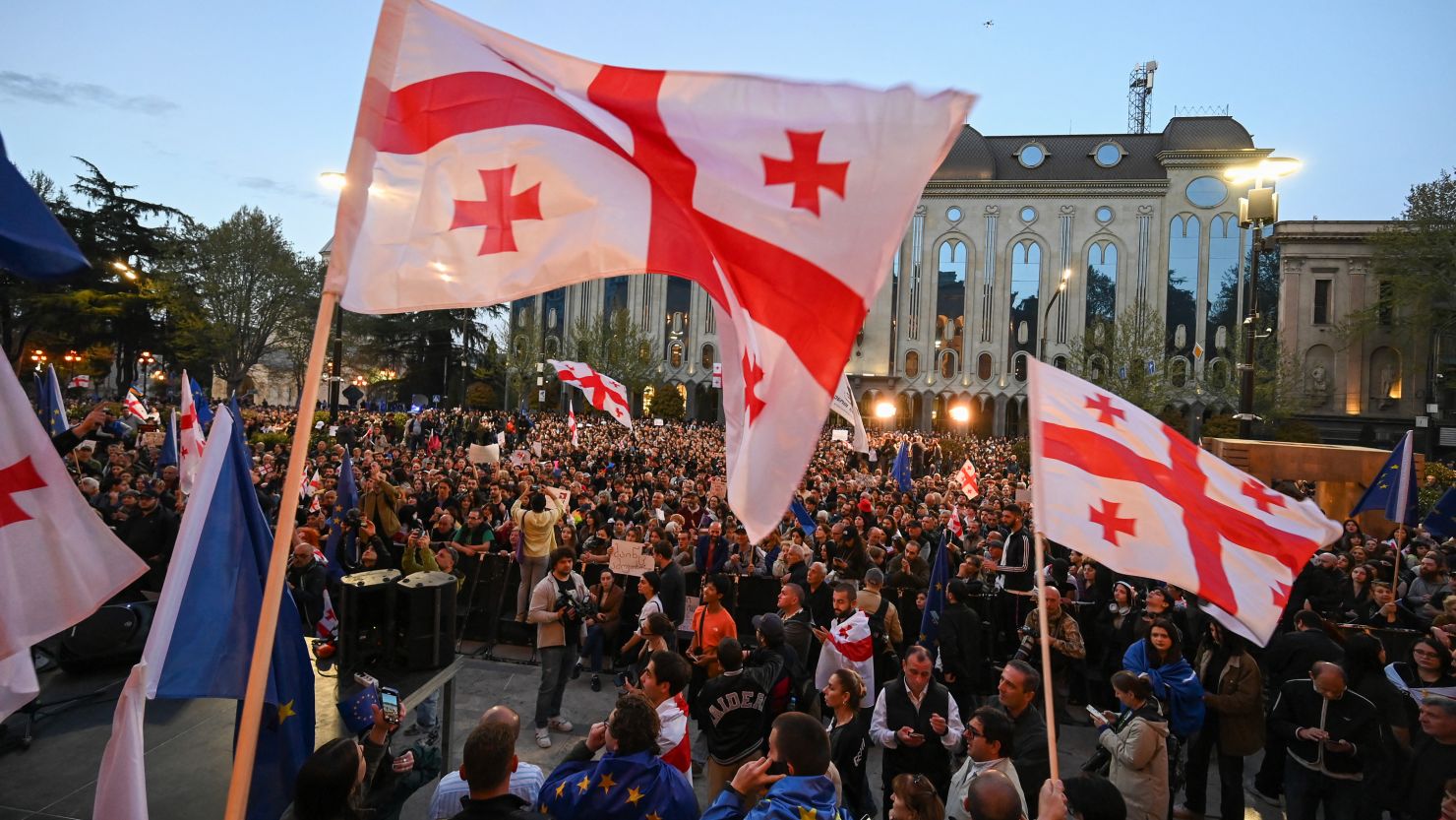 Georgian pro-democracy activists wave Georgia and European Union flags as they protest against a "foreign influence" bill outside the parliament in Tbilisi on April 15, 2024.