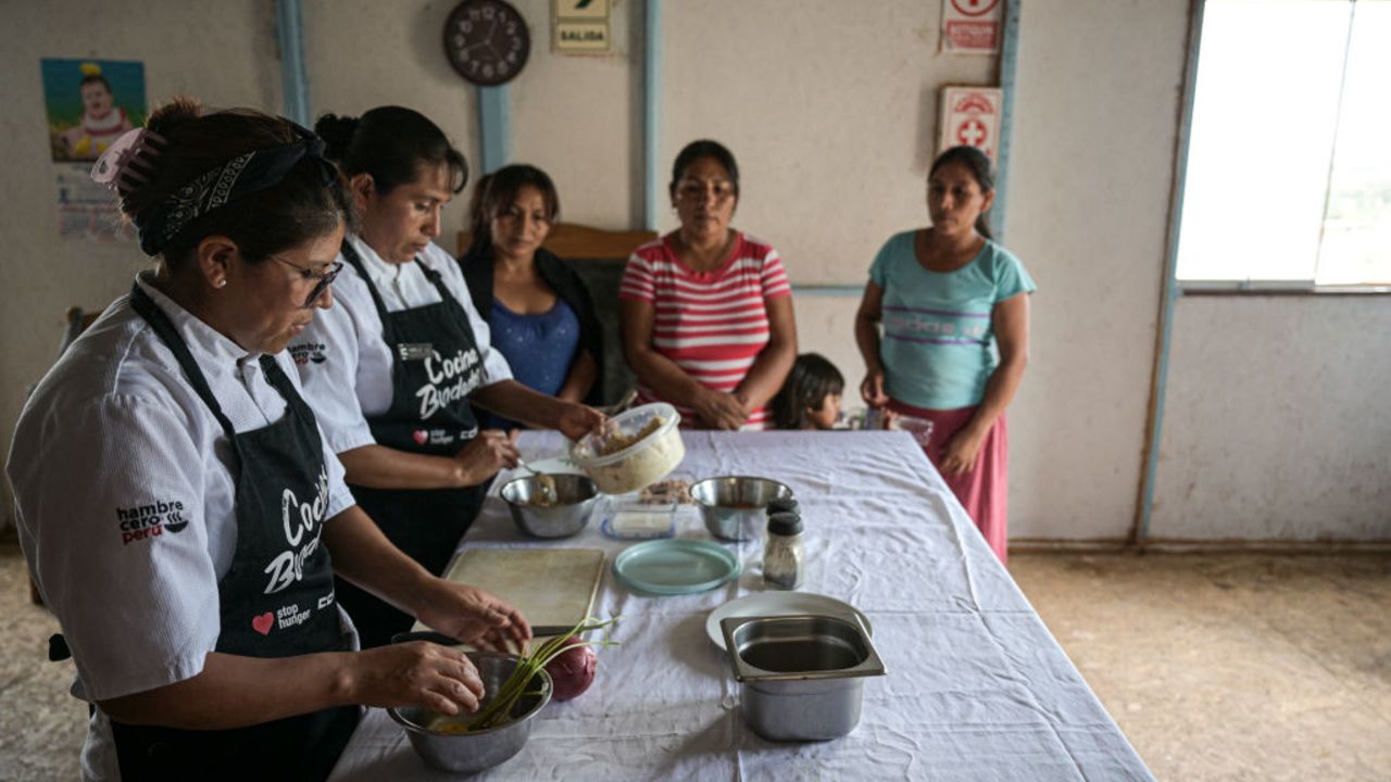 Melissa Castro (L), head chef at Ccori, an organization that promotes socio-environmental gastronomy with support from the French companies Sodexo and Stop Hunger, and Adeli Yanos, president of "Virgen del Rosario" soup kitchen, train a group of women to prepare a dish using the peels, leaves, and stems of vegetables and fruits at the soup kitchen in Lurin, in southern Lima, on April 11, 2024. Peruvian Chef Palmiro Ocampo launched a crusade in 2018 to not waste food. To do this, he shares his recipes with dozens of mothers from soup kitchens in poor areas of Lima and has managed to optimize more than a ton of ingredients that normally ended up in the trash and have been turned into delicious dishes. (Photo by Ernesto BENAVIDES / AFP) (Photo by ERNESTO BENAVIDES/AFP via Getty Images)