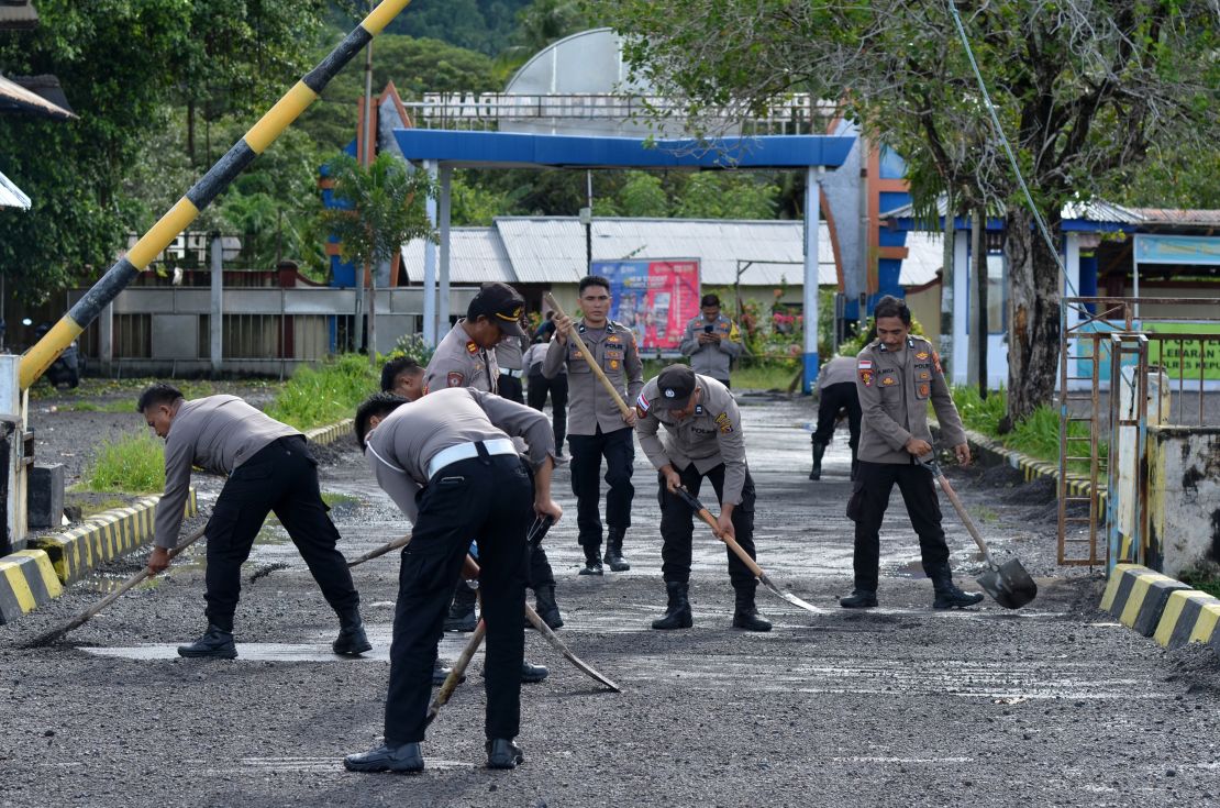 Police officers sweep volcanic material accumulated on the ground, after eruptions of the Mount Ruang volcano in North Sulawesi, Indonesia, on April 19, 2024.