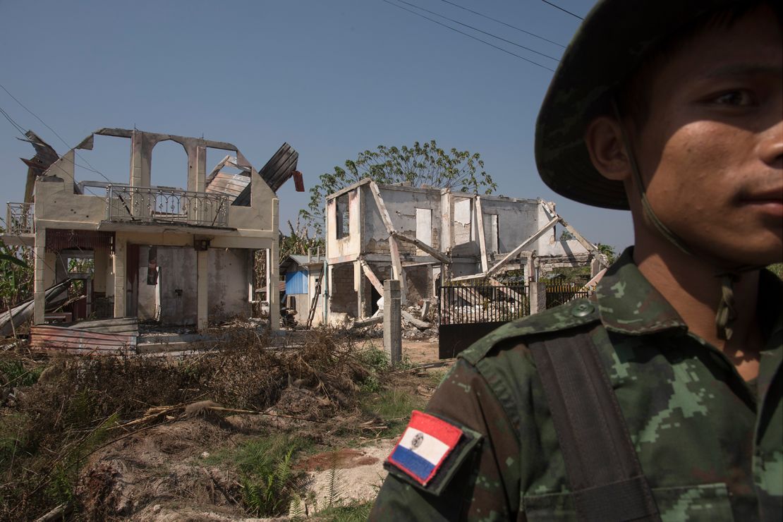 A soldier from the Karenni Nationalities Defense Force (KNDF) stands in front of houses destroyed by Burmese army artillery and airstrikes in Demoso, Myanmar on February 9, 2024.