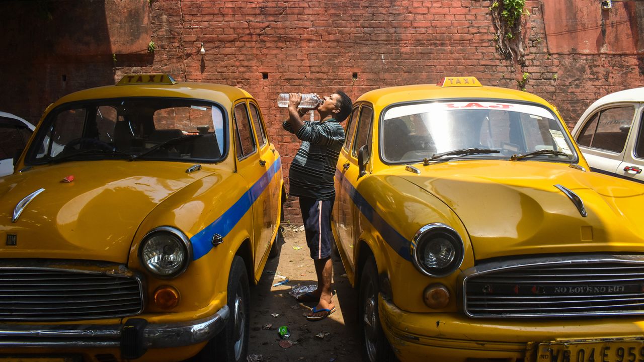 A taxi driver is drinking water at the taxi stand during the heat wave in Kolkata, India, on April 21, 2024.