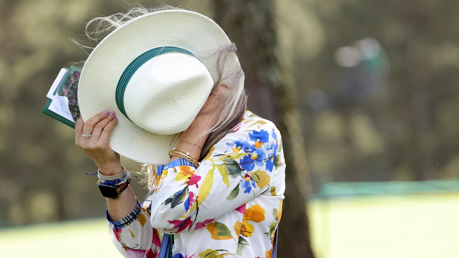 A patron shields herself with her hat from the wind during the second round of the 2024 Masters at Augusta National Golf Club in Augusta, Georgia.