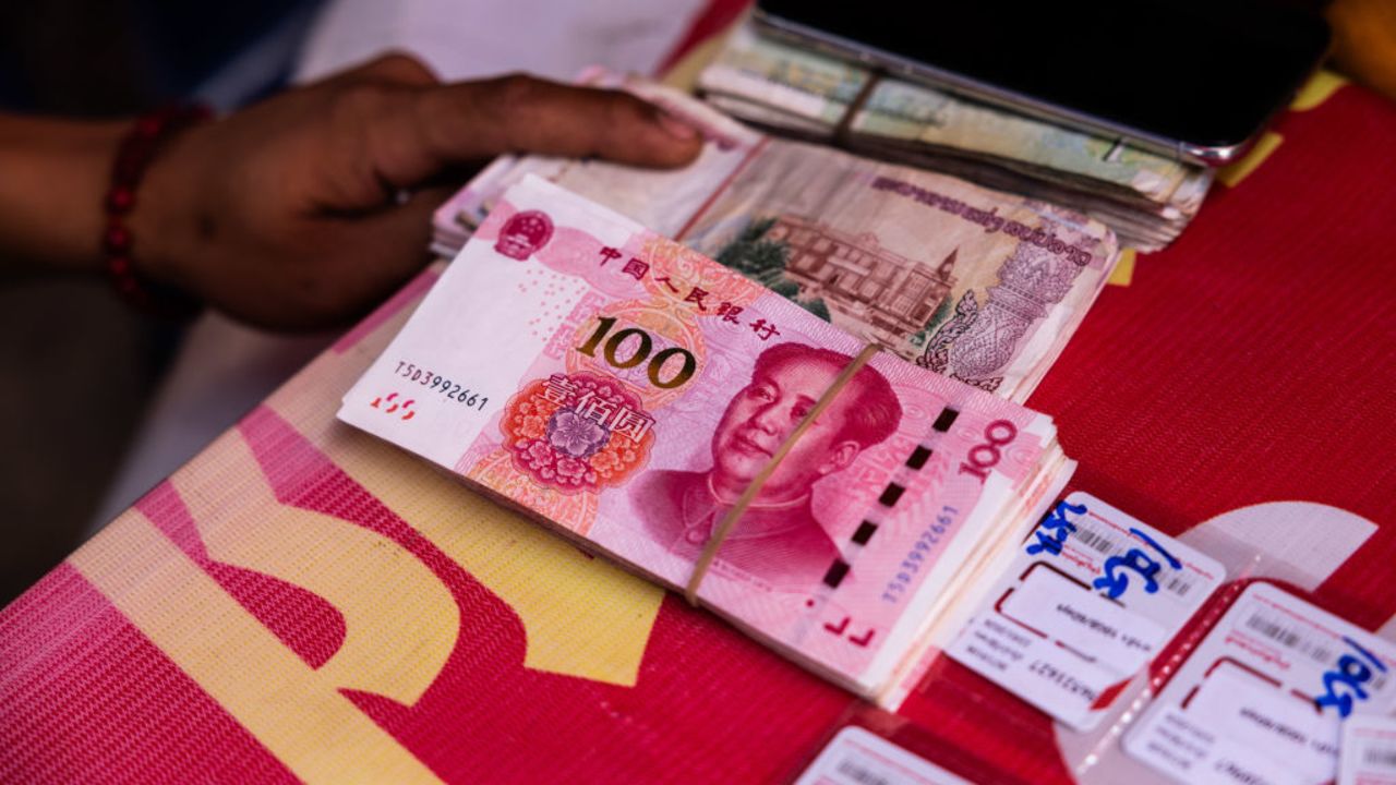 BOTEN, LAOS - APRIL 10: A SIM card vendor holds out Chinese currency in the Boten Special Economic Zone on April 10, 2024 in Boten, Laos. The Boten Special Economic Zone (SEZ), is a significant infrastructure project on the Laos border backed by a 10-billion-USD investment from China, was initially designed in 2003 and is set for completion in 2030. The SEZ is being built as an urban tourism and logistics hub. The China-Laos railway, a key project of China's Belt and Road Initiative, is a high-speed railway connecting Kunming, the capital of China's Yunnan province, to Vientiane, the capital of Laos. This railway is the biggest public infrastructure project ever undertaken by Laos, with a total length of 1,035 kilometers and a cost of US$5.9 billion, which is equivalent to around one-third of Laos' gross domestic product in 2019. The railway is dedicated to both passenger and freight traffic services, creating a new link between Laos and China, the former's neighbor and closest partner. The Laos section of the railway is part of a vision to build a Pan-Asia railway that will ultimately connect China, Laos, Thailand, Malaysia, and Singapore, improving the efficiency of goods movement for export-driven economies along the route, opening up travel and extending China's influence deep into Southeast Asia. (Photo by Lauren DeCicca/Getty Images)