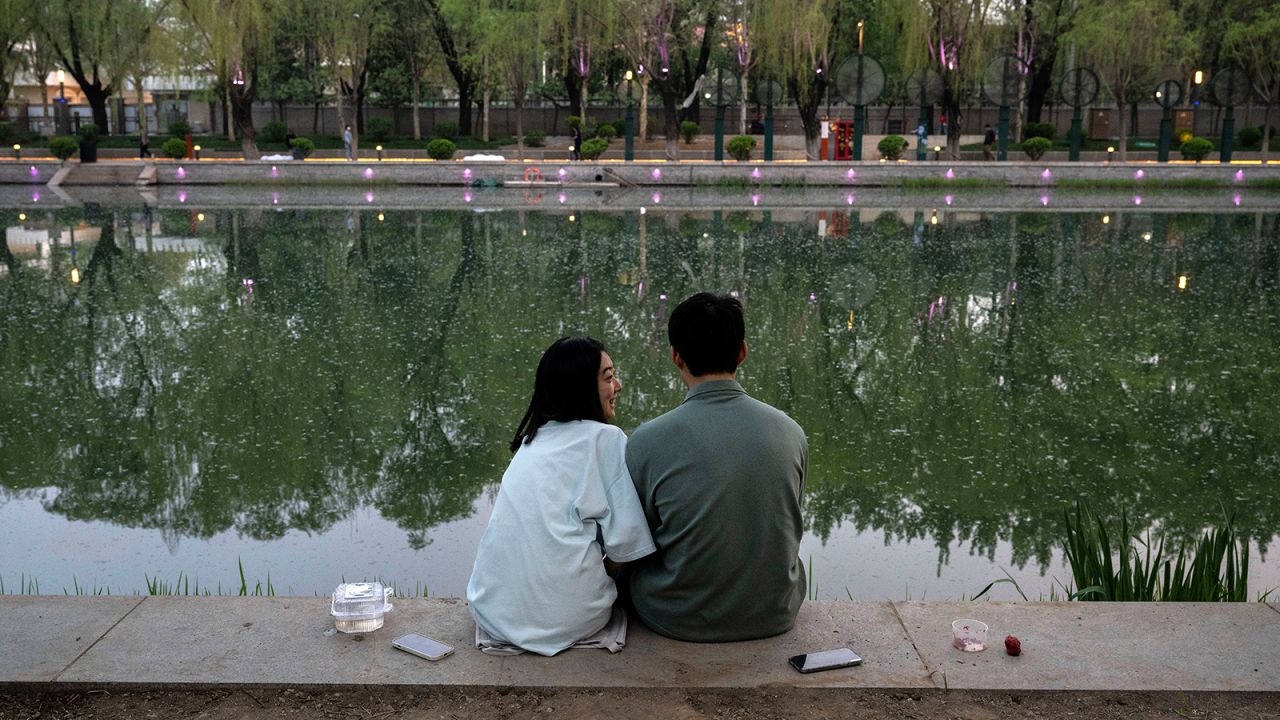 A couple sit together as they fish along a canal on April 12, 2024 in Beijing, China.