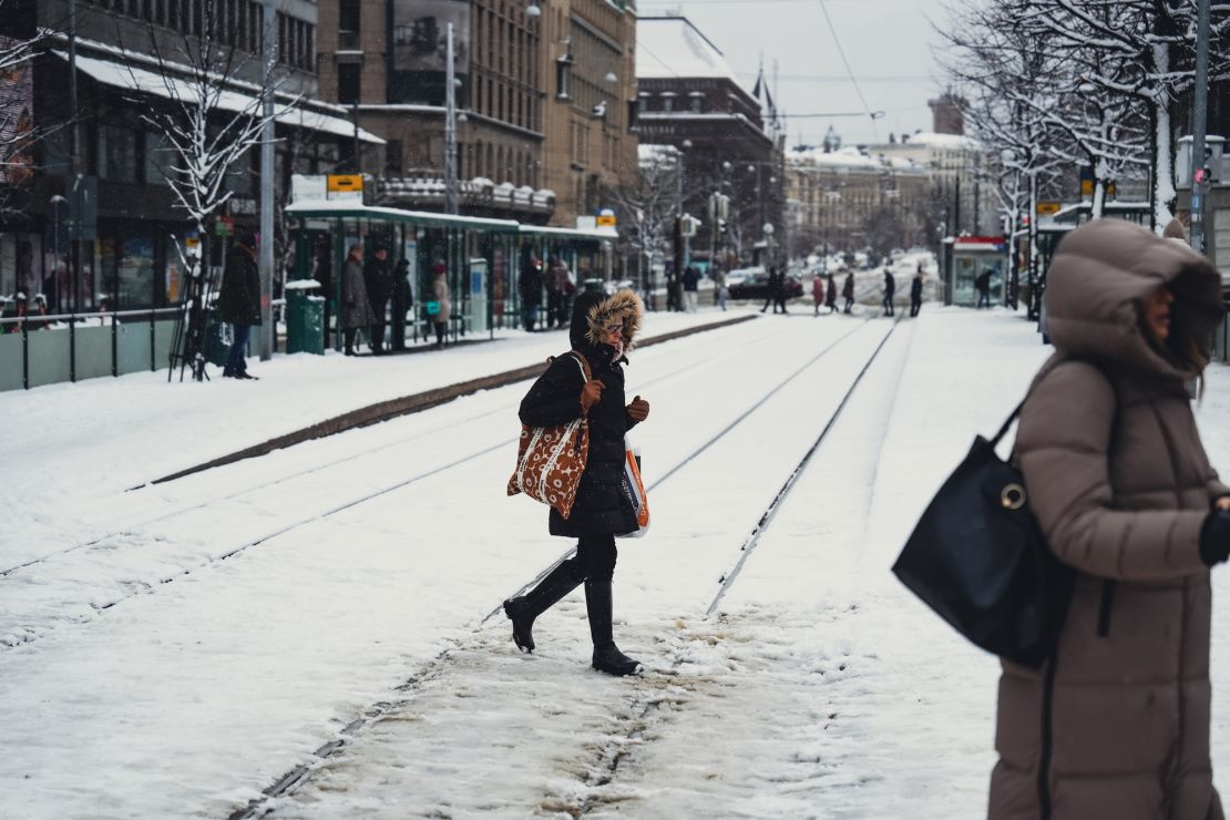 Ludzie przechodzą przez zaśnieżoną linię kolejową w Helsinkach w Finlandii, 23 kwietnia 2024 r. po tym, jak nietypowy system pogodowy zatrzymał tramwaje w mieście.