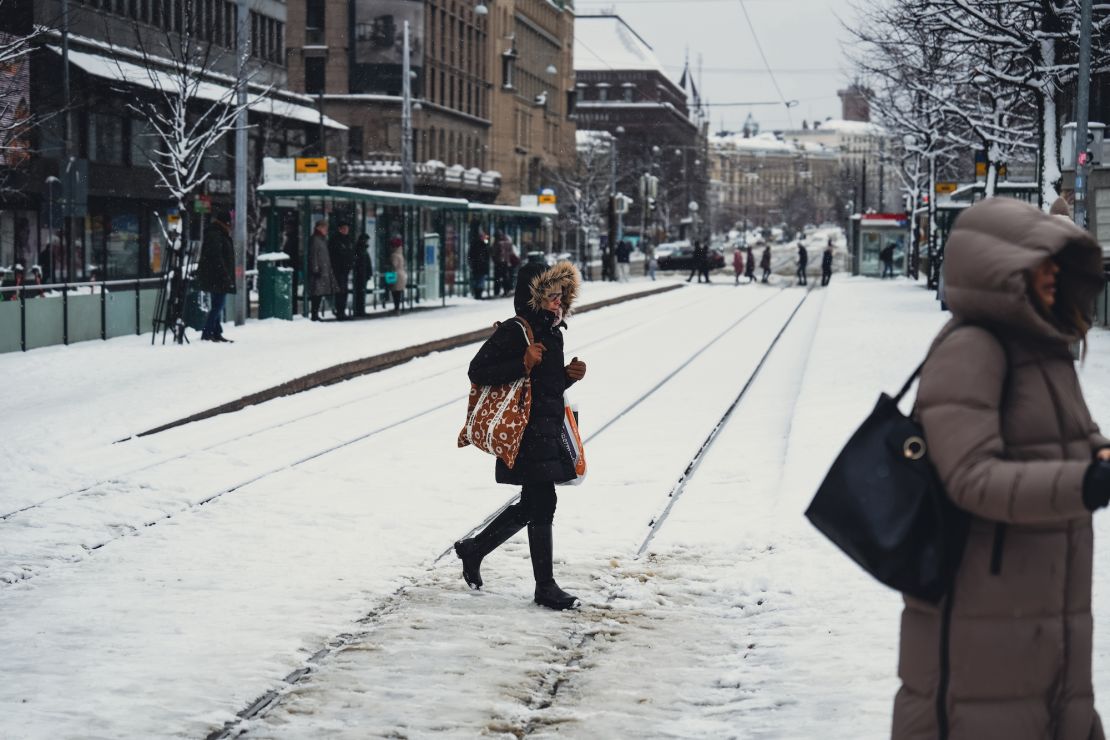 People cross a snow covered railway in Helsinki, Finland, on April 23, 2024, as an unusual weather system brought trams in the city to a halt.