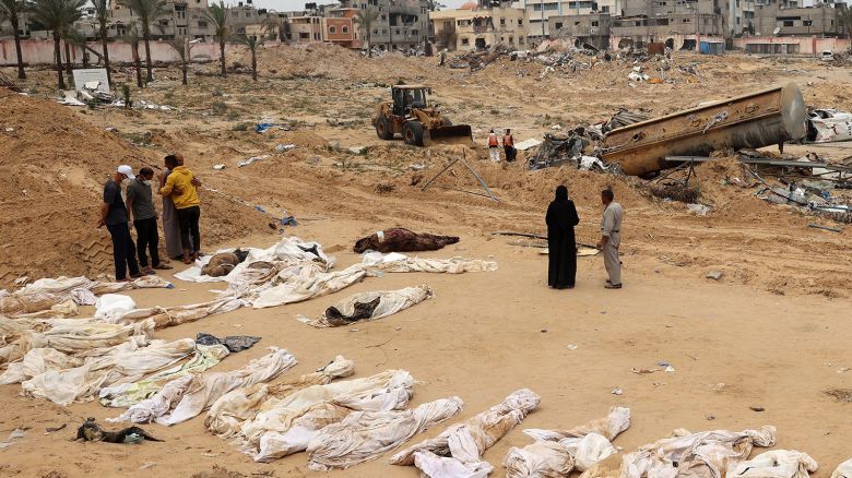 People gather near bodies lined up for identification after they were unearthed from a mass grave found in the Nasser Medical Complex in the southern Gaza Strip.