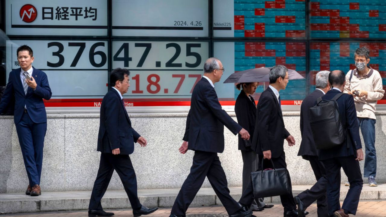 People walk in front of an electronic boarddisplaying a share price of the Nikkei index of the Tokyo Stock Exchange along a street in Tokyo on April 26, 2024. (Photo by Kazuhiro NOGI / AFP) (Photo by KAZUHIRO NOGI/AFP via Getty Images)