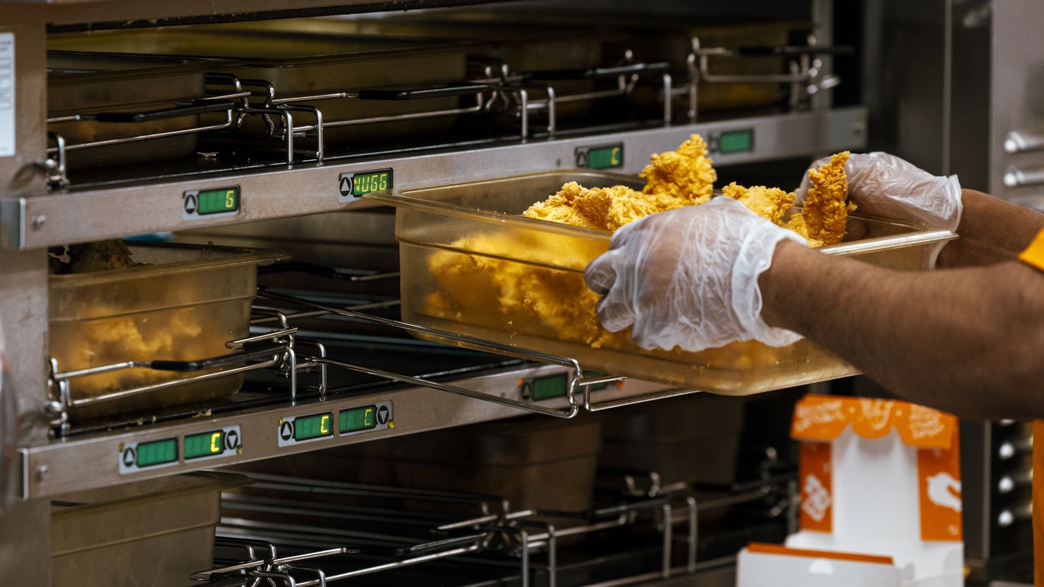 A worker holds a tray of fried chicken inside a Popeye's Louisiana Kitchen Inc. restaurant location in Latham, New York, US, on Thursday, April 25, 2024.