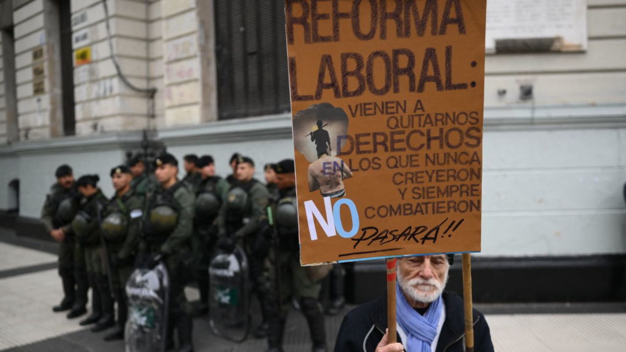 A man holds a placard against labor reform next to riot police as members of labor and social organizations march during a May Day (Labor Day) demonstration in Buenos Aires on May 1, 2024. (Photo by Luis ROBAYO / AFP) (Photo by LUIS ROBAYO/AFP via Getty Images)