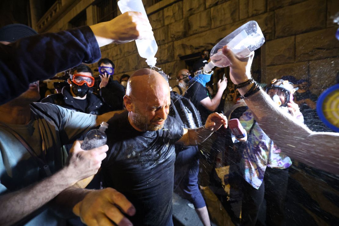Menschen versuchen, Tränengas aus den Augen eines Demonstranten zu entfernen, 1. Mai 2024.