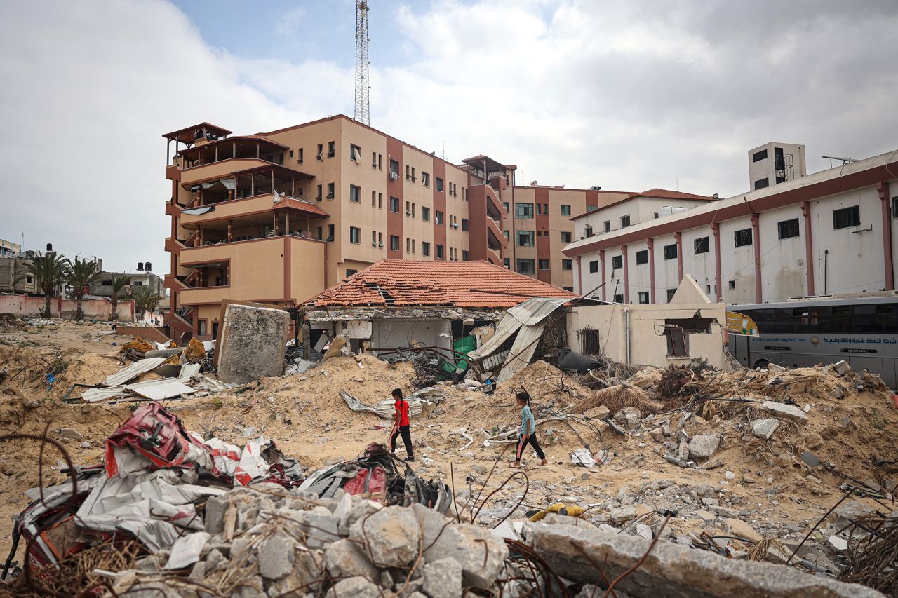 Palestinians walk on a ravaged road in front of Nasser Hospital, southern Gaza, on May 2.