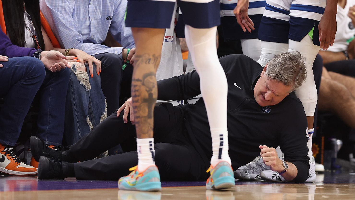 Minnesota Timberwolves head coach Chris Finch grabs his leg after a collision with a player during a game against the Phoenix Suns.
