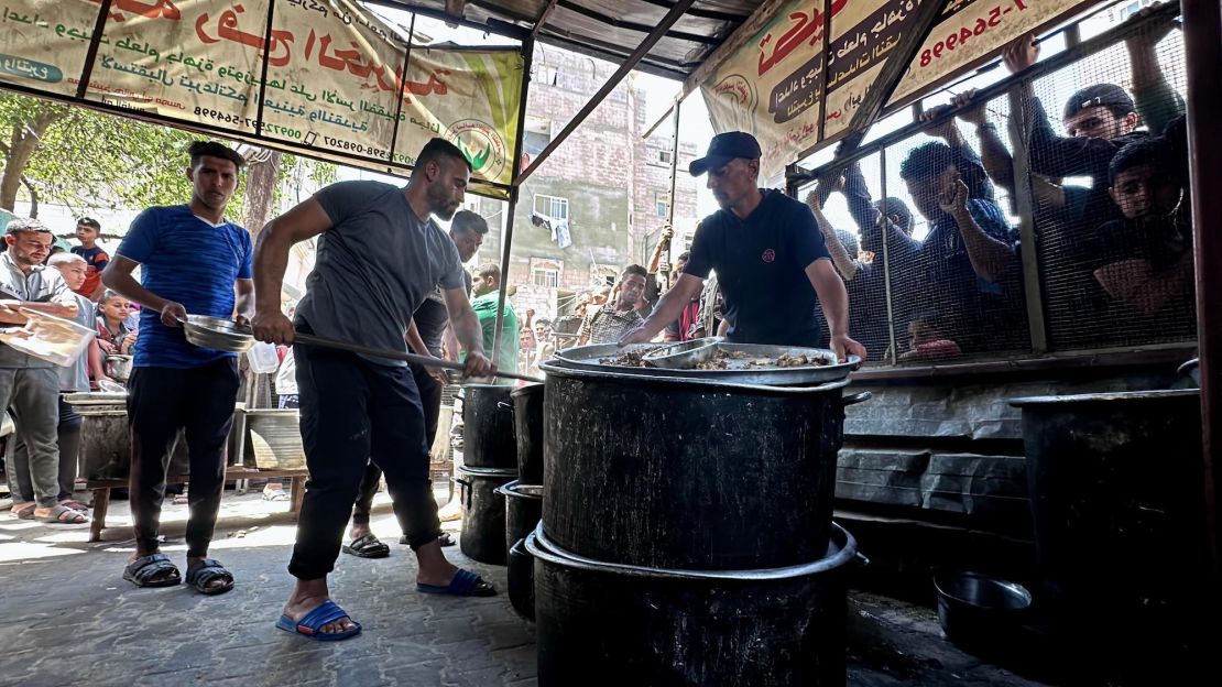 People in southern Gaza queue to receive a bowl of food for their families from charity organizations, on May 3, 2024.