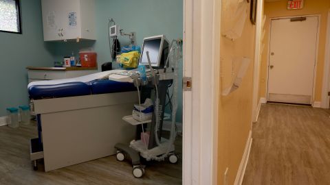 A health clinic examination room, viewed through a doorway. 