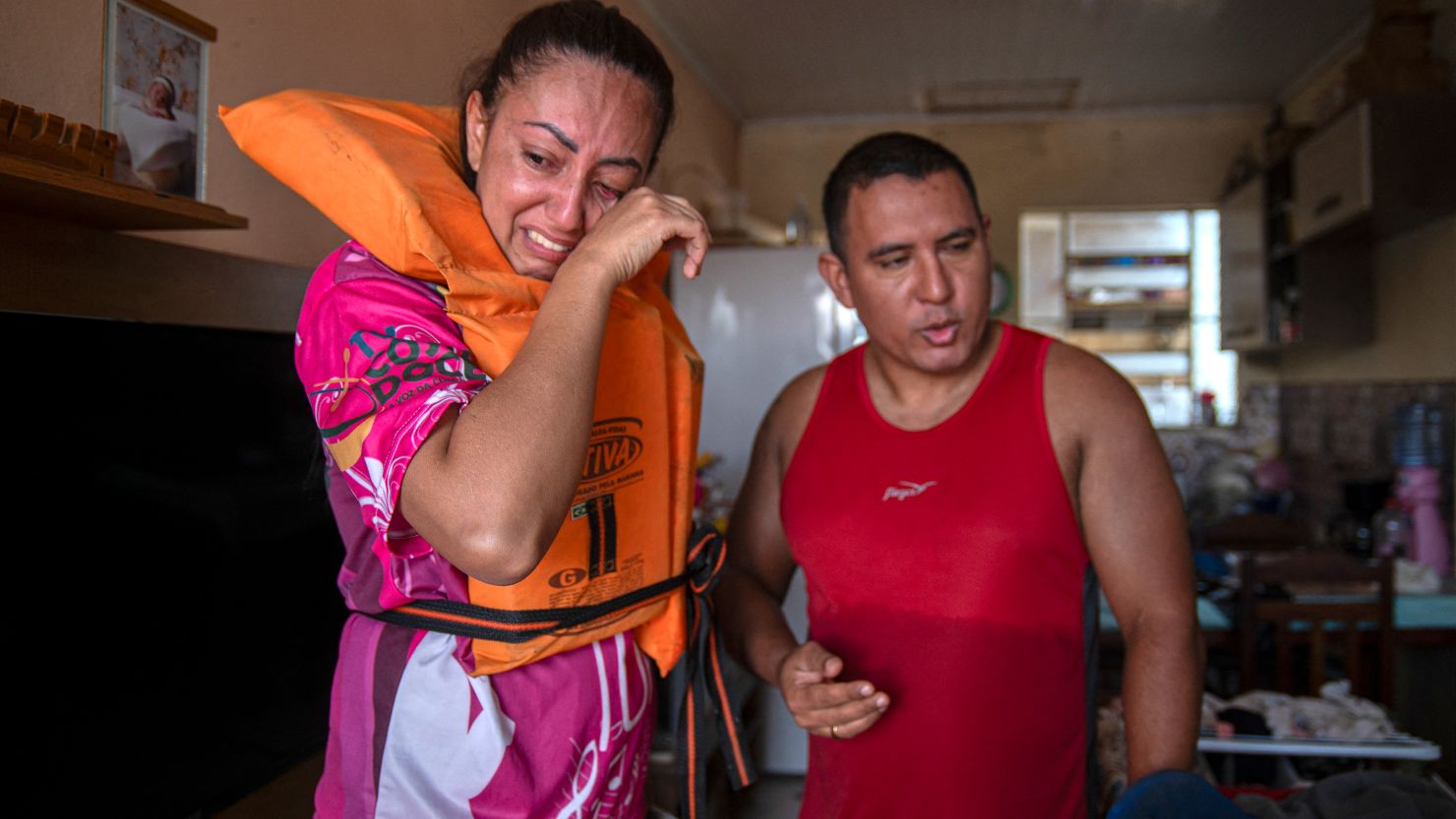 Katiane Mello (L) and her husband James Vargas cry before leaving their flooded home in Eldorado do Sul, Rio Grande do Sul state, Brazil, on May 9, 2024.