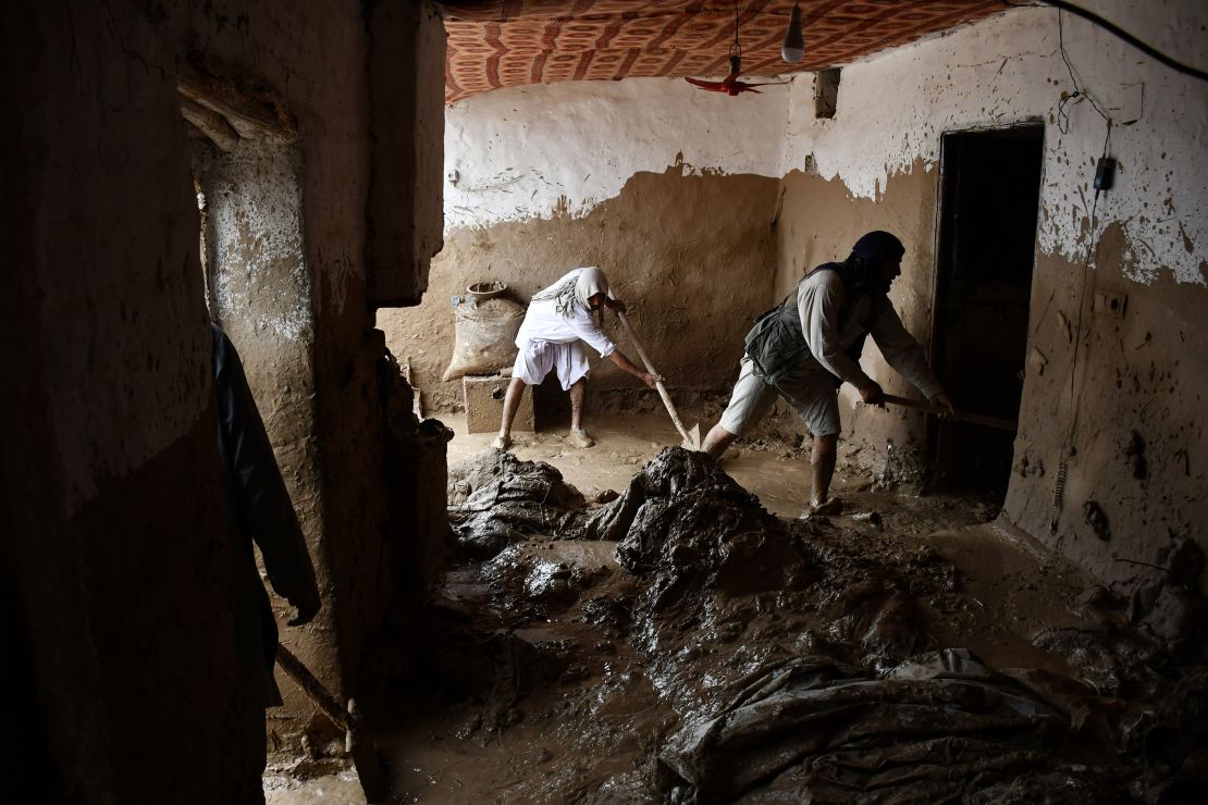 Afghan men shovel mud from a house following flash floods.