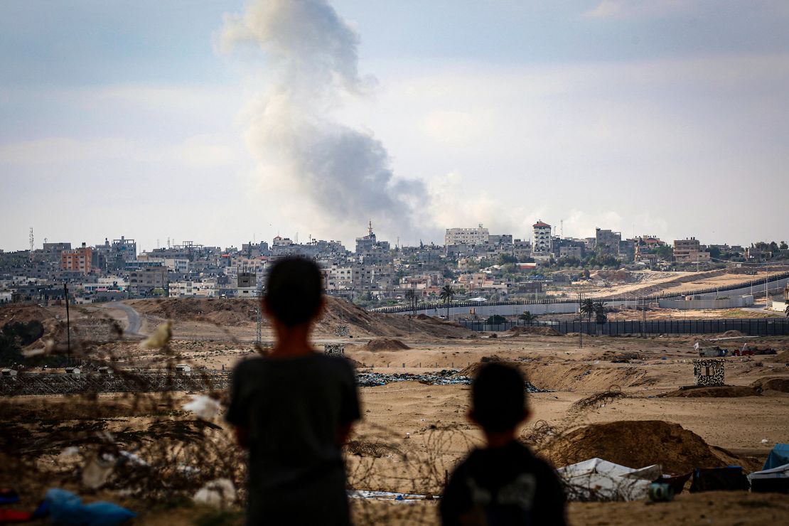Çocuklar Pazartesi günü İsrail'in Gazze Şeridi'nin güneyinde Refah'ın doğusundaki baskınları sırasında yükselen dumanları izliyor.