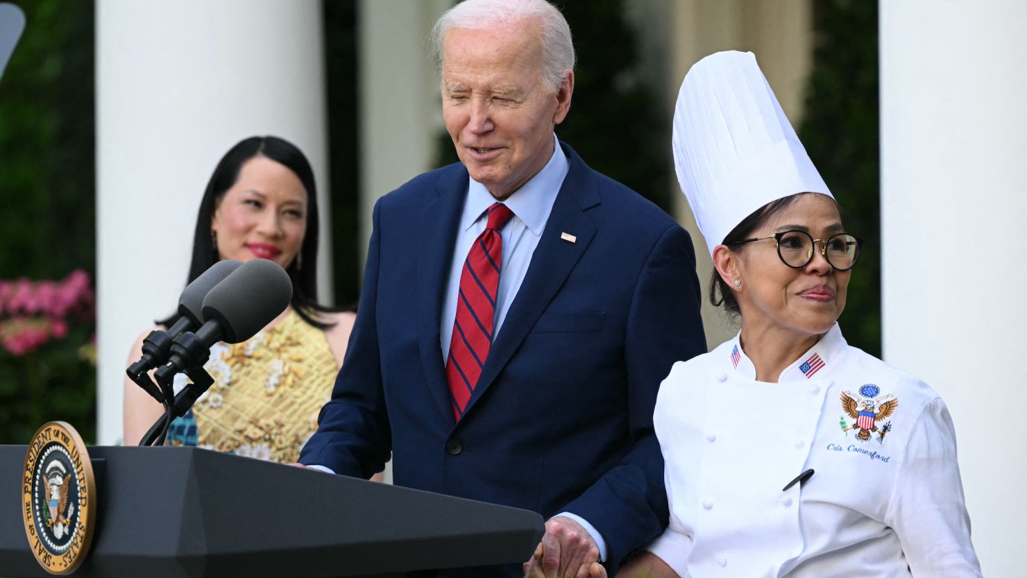 US actress Lucy Liu, left, watches as President Joe Biden brings to the podium White House chef Cristeta Comerford during a reception celebrating Asian American, Native Hawaiian and Pacific Islander Heritage Month in the Rose Garden of the White House on May 13, 2024.