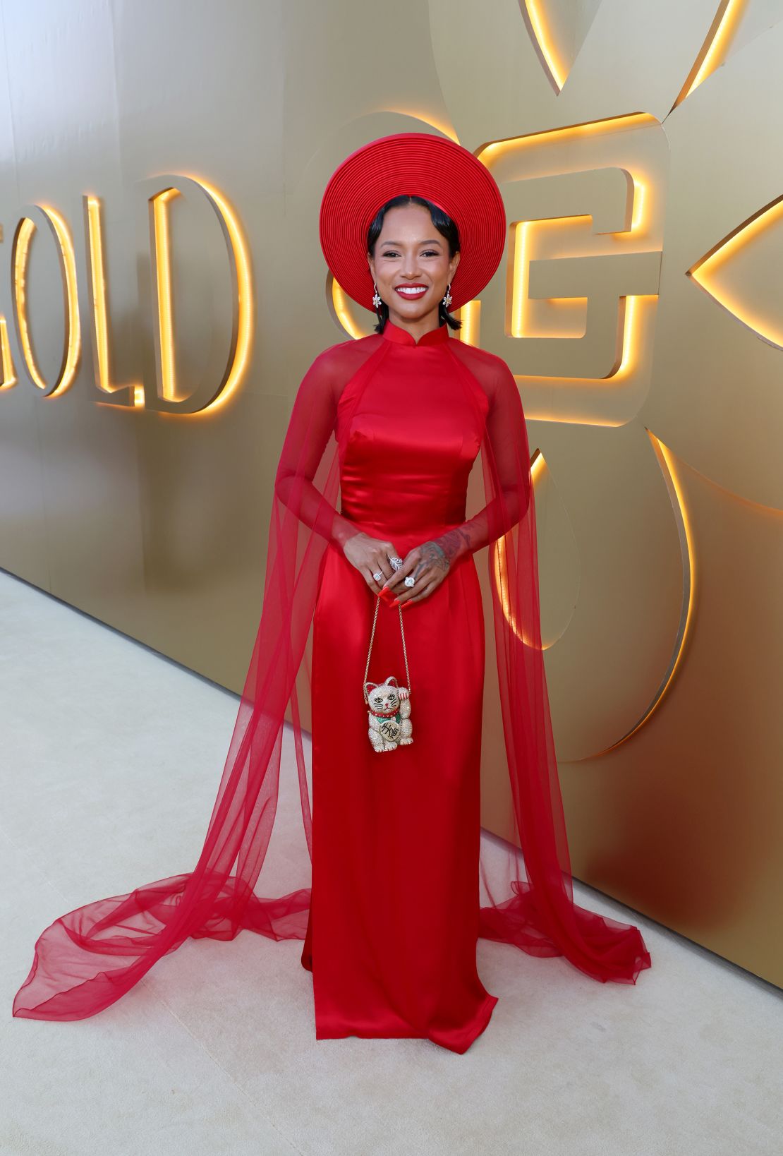 Tran apareceu com um vestido dramático de coluna de cetim desenhado por Thai Nguyen Atelier, completo com uma capa de tule e uma bolsa de gato da sorte enfeitada com joias.