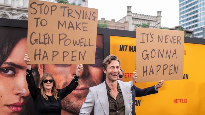 US actor Glen Powell's parents hold up signs behind him as they attend the special screening of "Hitman" at the Paramount Theatre in Austin, Texas, on May 15, 2024.