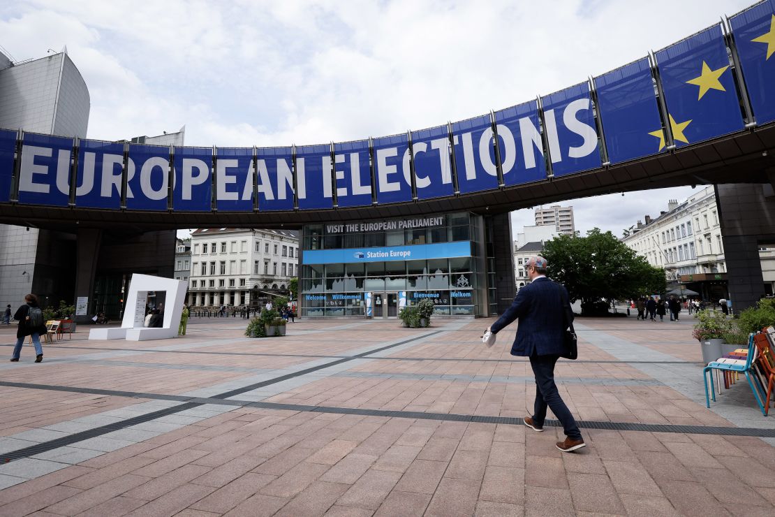 Pedestrians walk past a banner displayed on the building of the European Parliament in Brussels on May 17, 2024.