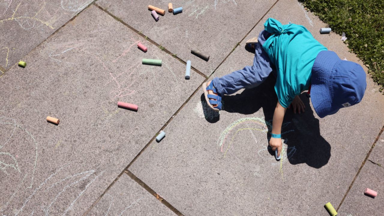 WASHINGTON, DC - MAY 13: A child plays with chalk during the Our Babies 1st: Restore The Pay Equity Fund rally at Freedom Plaza on May 13, 2024 in Washington, DC. (Photo by Jemal Countess/Getty Images for SPACEs In Action)