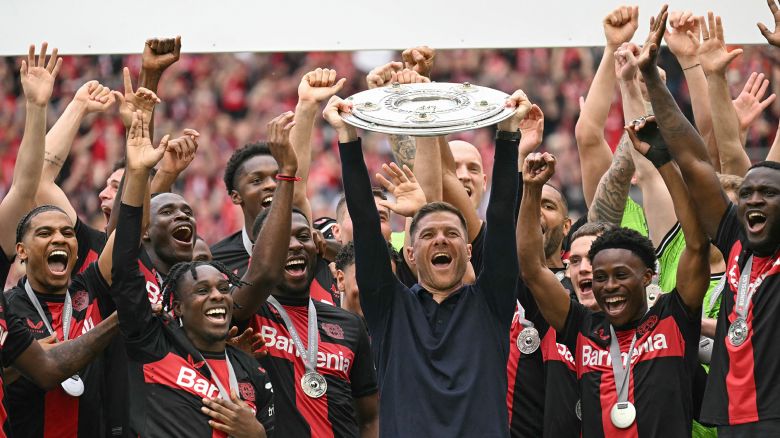 TOPSHOT - Bayer Leverkusen's Spanish head coach Xabi Alonso and his players celebrate with the Bundesliga trophy after the German first division Bundesliga football match between Bayer 04 Leverkusen and FC Augsburg in Leverkusen, western Germany on May 18, 2024. (Photo by INA FASSBENDER / AFP) / DFL REGULATIONS PROHIBIT ANY USE OF PHOTOGRAPHS AS IMAGE SEQUENCES AND/OR QUASI-VIDEO (Photo by INA FASSBENDER/AFP via Getty Images)