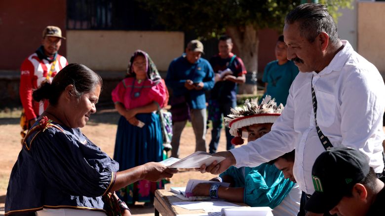 A Wixarika Indigenous woman hands out documents during a mock election day drill, as part of the training given by officials of the National Electoral Institute ahead of the upcoming June 2 elections in Tuxpan de Bolaños, Jalisco State, Mexico, on May 18, 2024. The upcoming election will be the largest in the country's history.