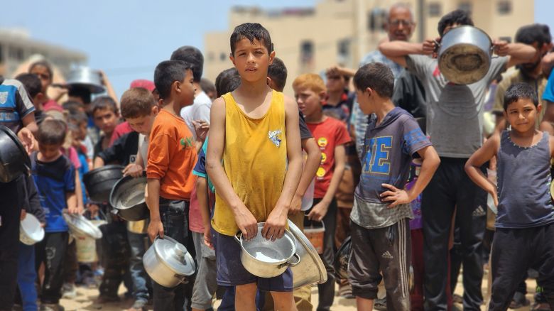 Palestinian children wait in line with pots to collect food in Rafah, southern Gaza on May 19, 2024.