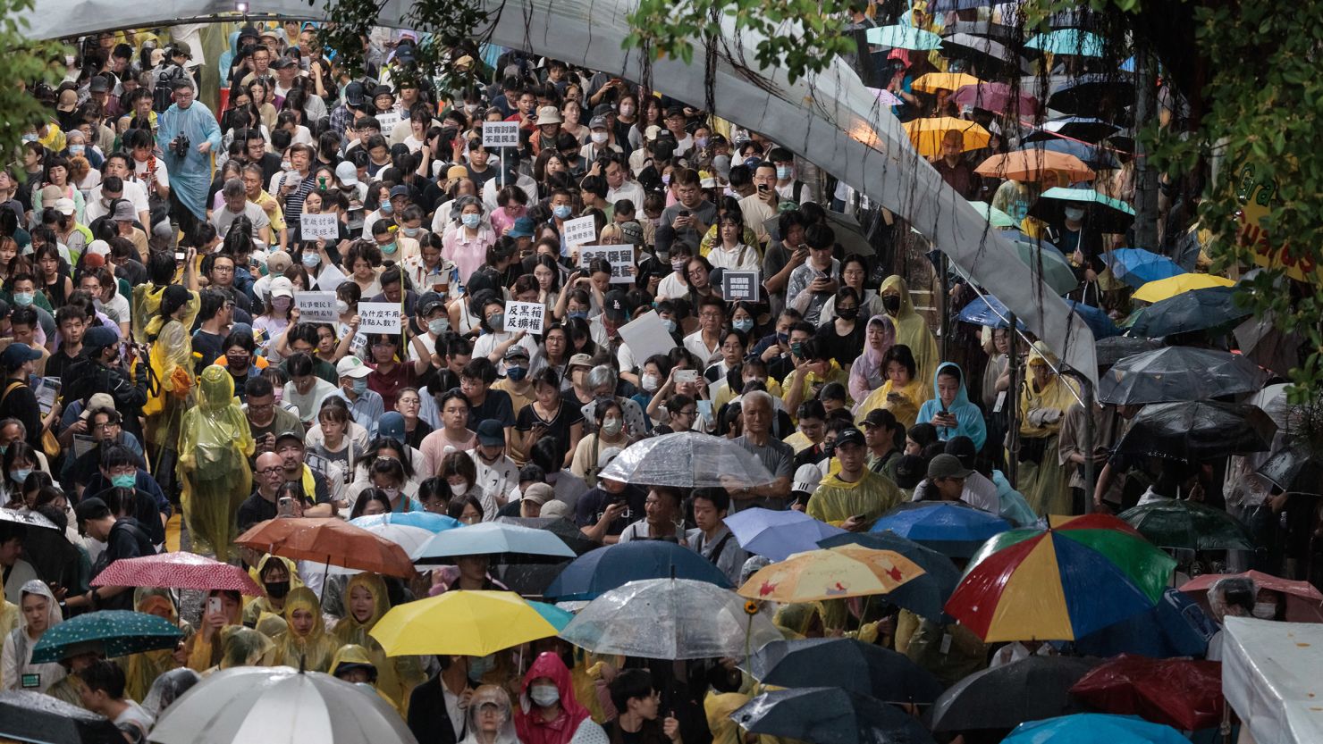 Protesters hold up umbrellas in the rain at a rally outside Taiwan's legislature against a proposed bill by opposition parties to impose greater scrutiny on the executive branch of government on May 21, 2024.