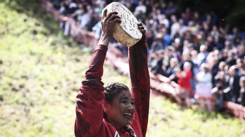 Abby Lampe celebrates after competing in the annual Cooper's Hill cheese rolling competition near the village of Brockworth, Gloucester, in western England.