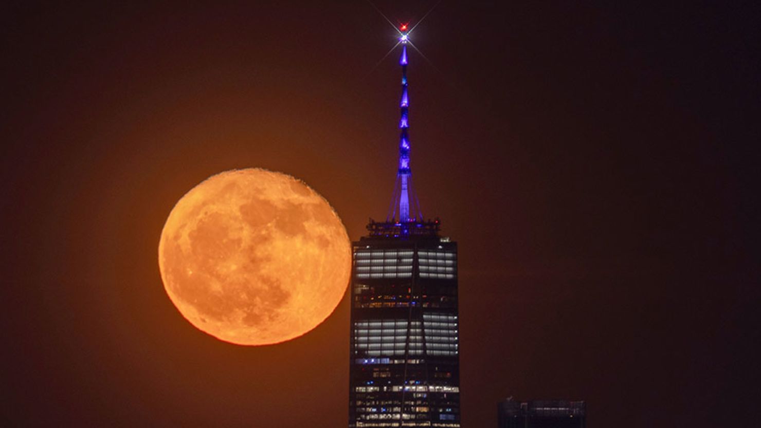 The flower moon rises behind the skyline of lower Manhattan and One World Trade Center in New York City on May 24, 2024.