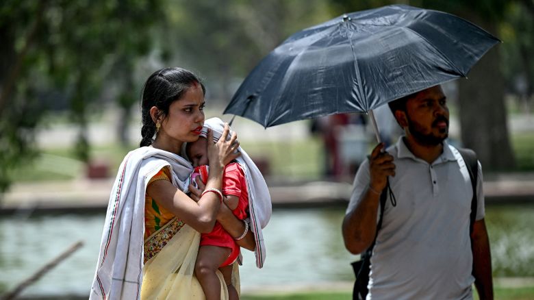 A woman shields her child from the sun during severe heatwave on a hot summer day in New Delhi on May 29, 2024. Temperatures in India's capital have soared to a record-high 49.9 degrees Celsius (121.8 Fahrenheit) as authorities warn of water shortages in the sprawling mega-city. (Photo by Money SHARMA / AFP) (Photo by MONEY SHARMA/AFP via Getty Images)