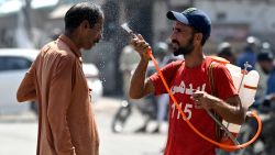 A volunteer sprays water on a bypasser's face along a street during a hot summer day in Karachi on May 30, 2024, amid the ongoing heatwave. (Photo by Asif HASSAN / AFP) (Photo by ASIF HASSAN/AFP via Getty Images)