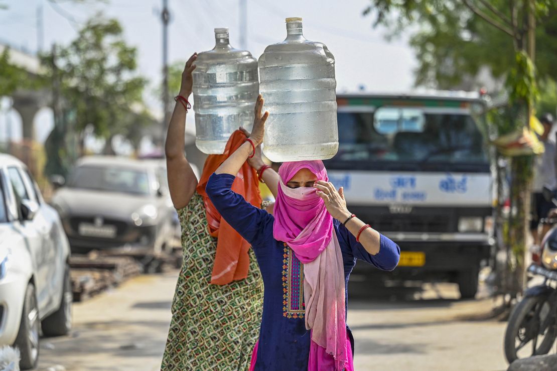 People are filling up from a water tanker during a heat wave in New Delhi, India, on June 3, 2024. In the blazing heat, people wait in long lines, hoping to fill at least one bucket.