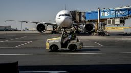A ground staff drives a baggage tug vehicle past an Emirates Boeing 777-200 aircraft connected to a jet bridge for boarding on the tarmac at Cairo International Airport in Cairo on June 3, 2024. (Photo by Amir MAKAR / AFP) (Photo by AMIR MAKAR/AFP via Getty Images)