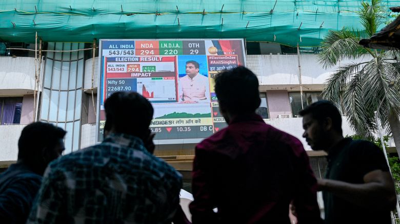 Pedestrians watch share prices on a digital broadcast outside the Bombay Stock Exchange (BSE) on the day of India's general election result in Mumbai on June 4, 2024.
