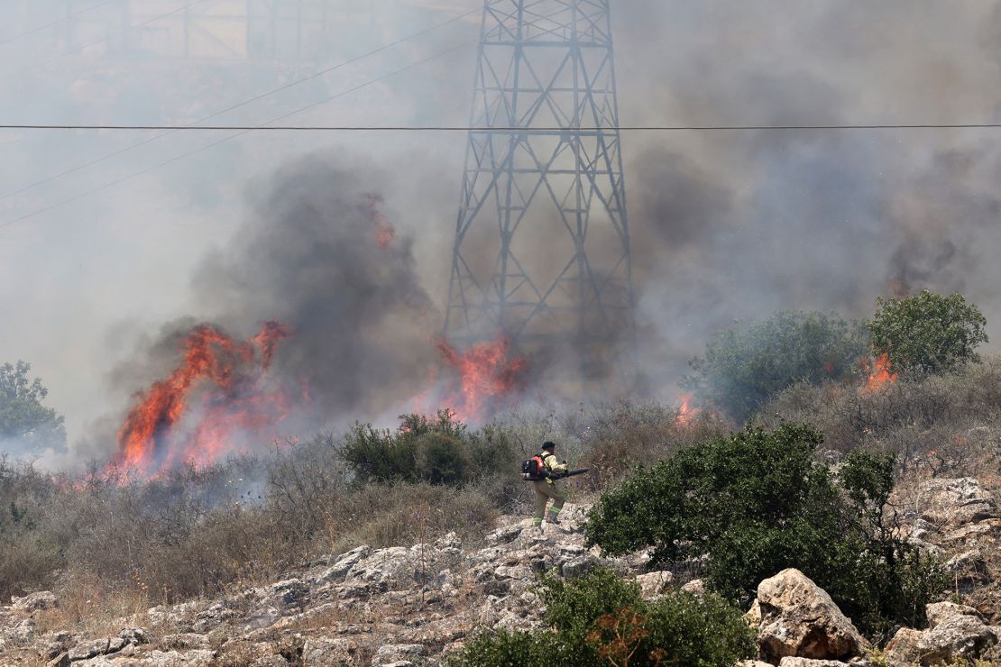 An Israeli firefighter walks near the flames in a field after rockets launched from southern Lebanon landed on the outskirts of Alma in the Israel-annexed Golan Heights in Syria on Tuesday.