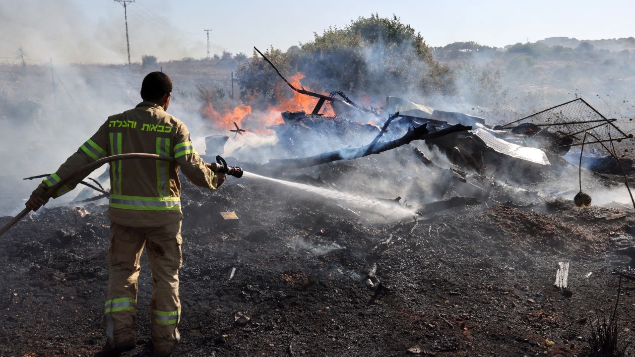 An Israeli firefighter puts out flames in a field after rockets launched from southern Lebanon landed on the outskirts of Kiryat Shmona, on June 4, 2024. Since the outbreak of war between the Palestinian militant group Hamas and Israel on October 7, the Lebanese-Israeli border area has witnessed near-daily exchanges of fire, mainly between the Israeli army and Hamas ally Hezbollah. (Photo by JACK GUEZ / AFP) (Photo by JACK GUEZ/AFP via Getty Images)