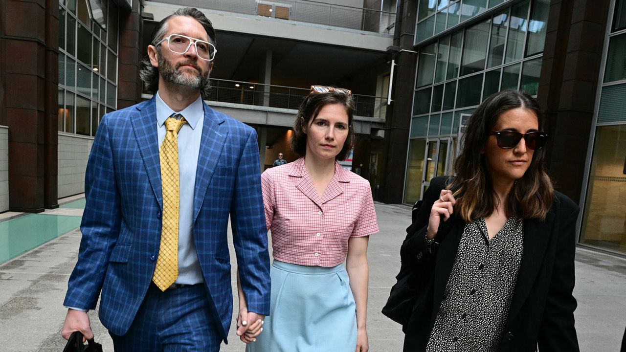TOPSHOT - US Amanda Knox arrives with her husband Christopher Robinson (L) at the courthouse in Florence, on June 5, 2024 before a hearing in a slander case, related to her jailing and later acquittal for the murder of her British roommate in 2007. The American was only 20 when she and her Italian then-boyfriend were arrested for the brutal killing of 21-year-old fellow student Meredith Kercher at the girls' shared home in Perugia. The murder began a long legal saga where Knox was found guilty, acquitted, found guilty again and finally cleared of all charges in 2015. (Photo by Tiziana FABI / AFP) (Photo by TIZIANA FABI/AFP via Getty Images)