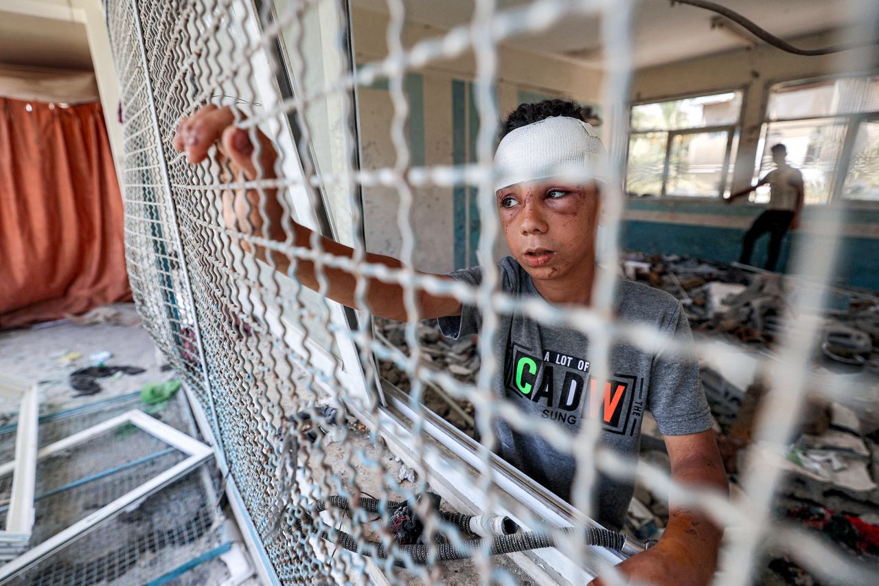 An injured boy stands by a window lattice in a destroyed classroom where people were sheltering at a school run by the UN Relief and Works Agency for Palestine Refugees (UNRWA) in the Nuseirat camp in central Gaza on June 7.