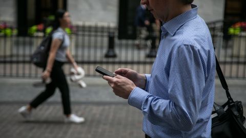 A pedestrian holding a smartphone in front of the New York Stock Exchange (NYSE) in New York, US, on Friday, June 7, 2024.