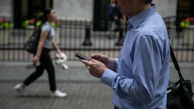 A pedestrian holding a smartphone in front of the New York Stock Exchange (NYSE) in New York, US, on Friday, June 7, 2024.