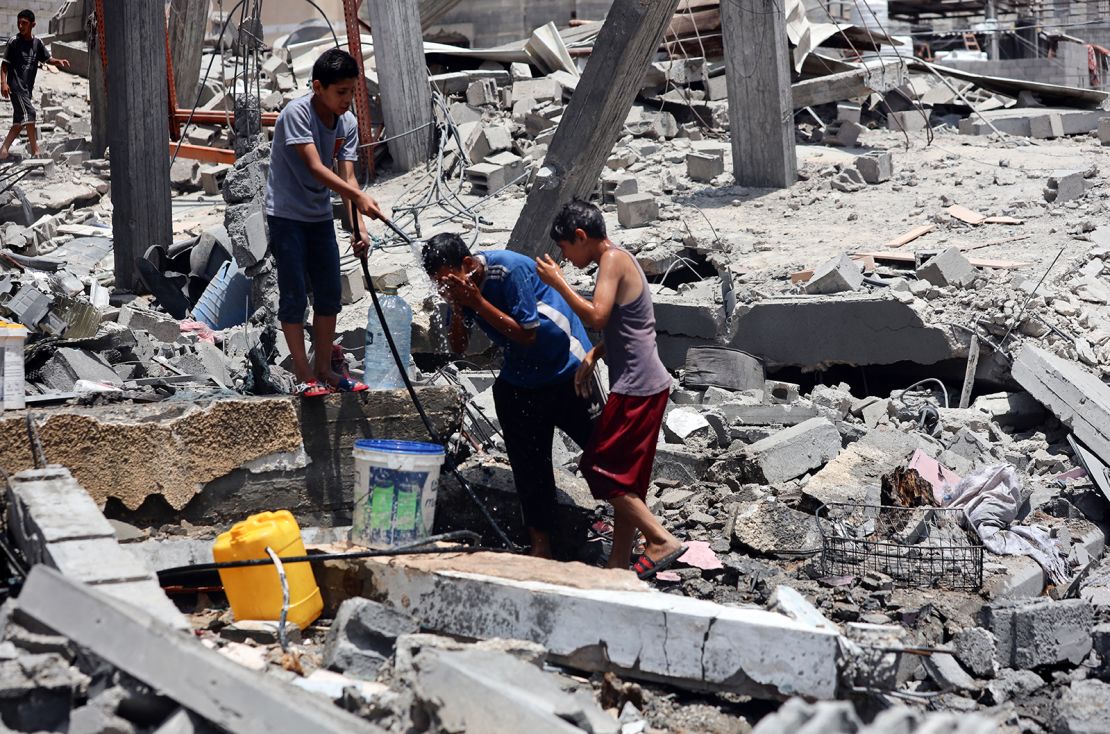 Palestinian children cool off and fill up water jugs in the Nuseirat refugee camp, in central Gaza, amid a heatwave on June 9, a day after a deadly operation by Israeli forces to rescue hostages.