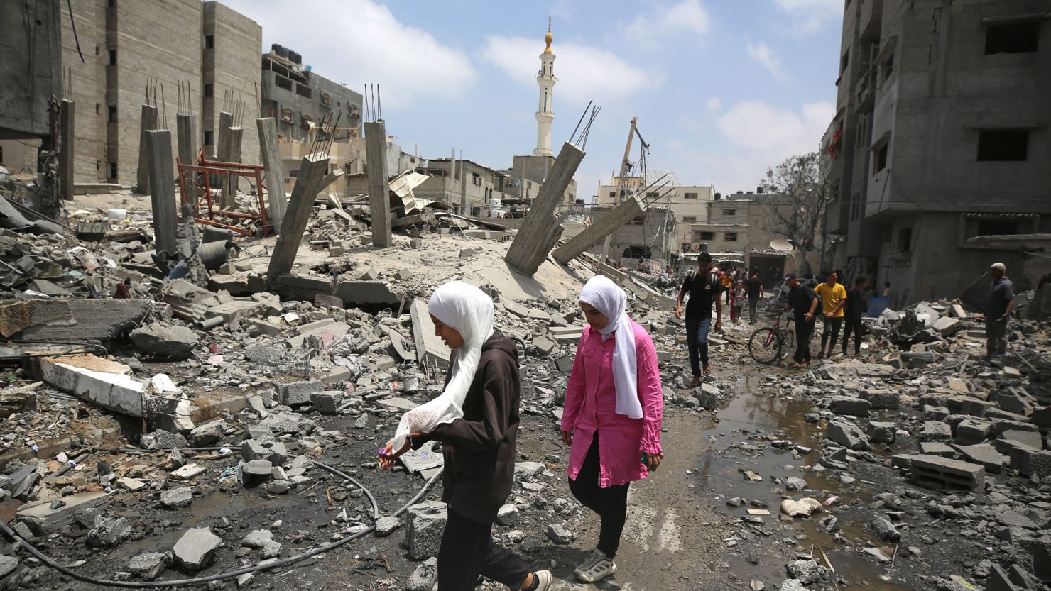 Palestinians walk past debris a day after an operation by the Israeli Special Forces in the Nuseirat camp, in the central Gaza Strip, on June 9, 2024.