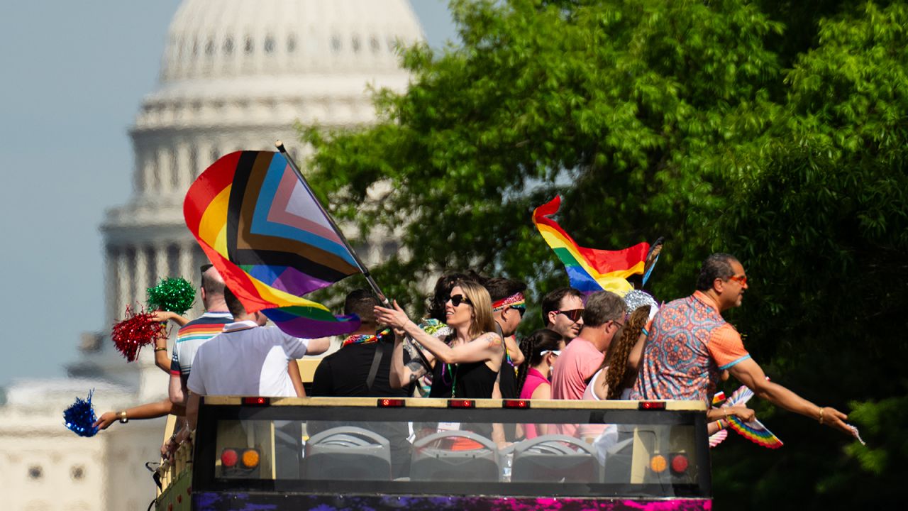 Parade participants wave from the top of a double decker tour bus as Capital Pride Parade makes its way down Pennsylvania Ave. NW on June 8, 2024.